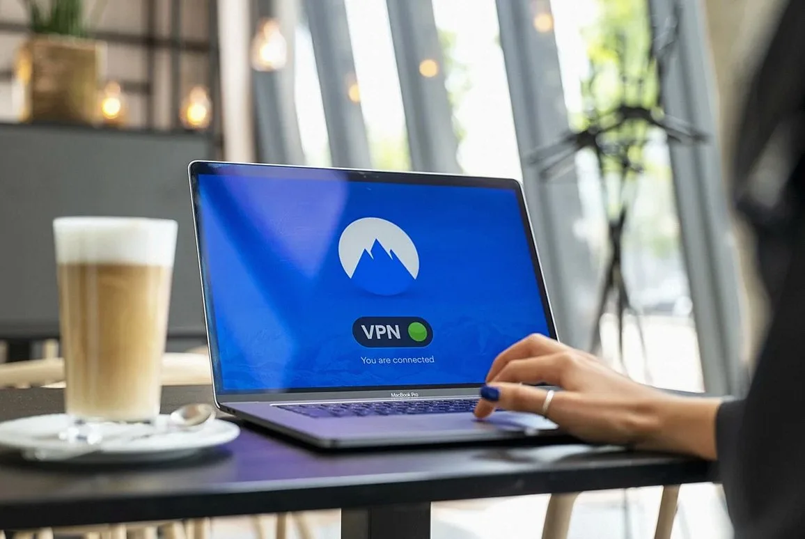 カフェでノートパソコンを操作する人。画面にはVPNアプリが表示されている